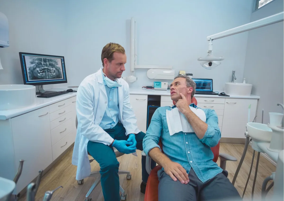 Patient discussing tooth replacement options with a dentist when comparing a dental bridge and dental implant.