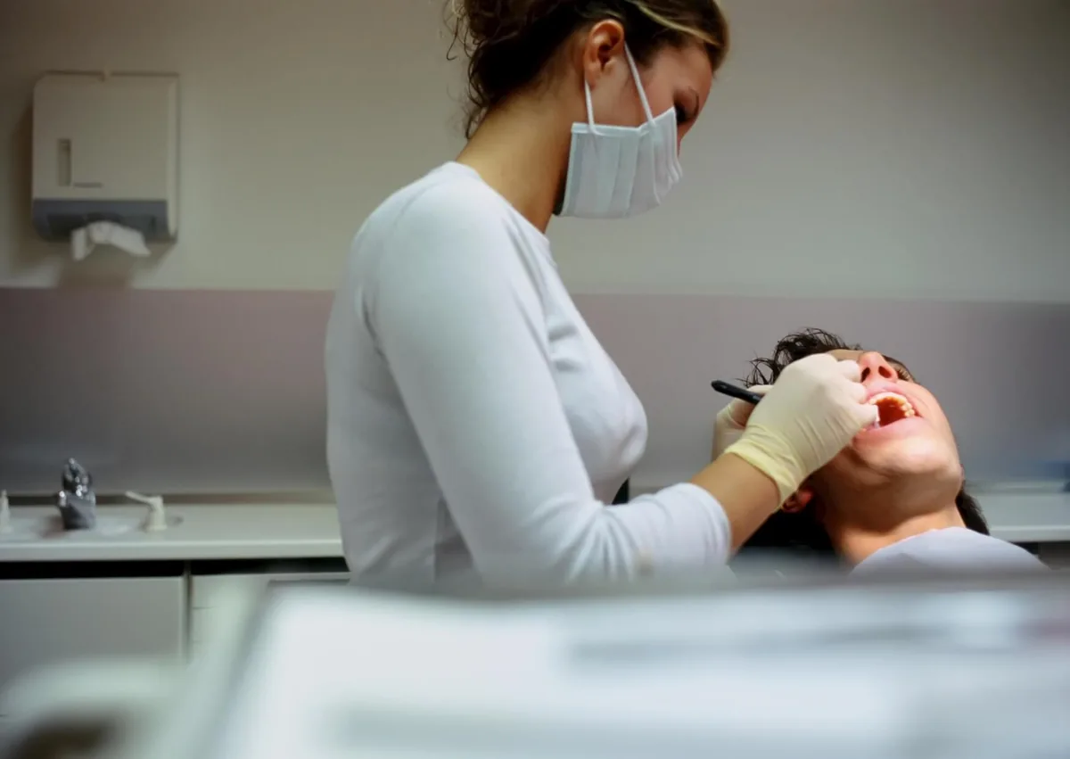 Dentist examining a patient’s teeth during a checkup to help maintain dental implants for long-term use.