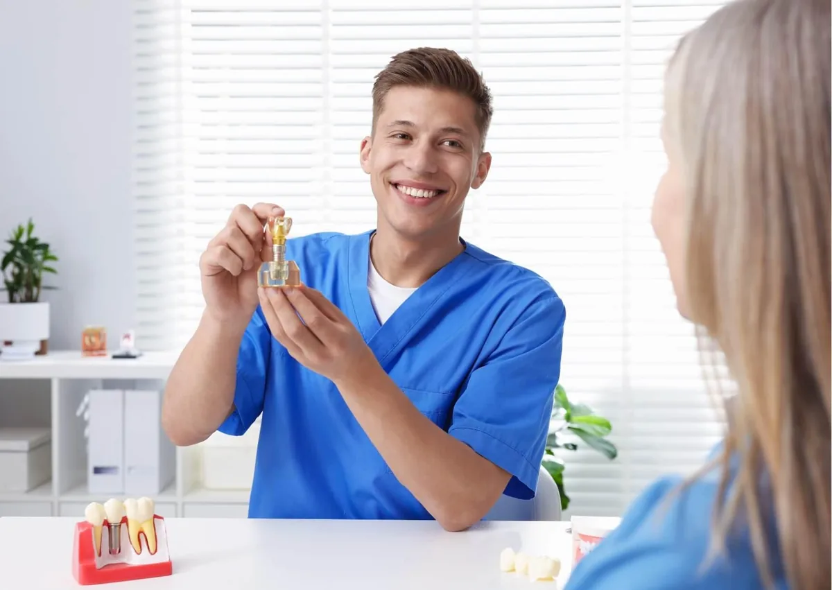 Dentist showing a dental implant model to a patient while discussing single tooth implant cost and treatment options.