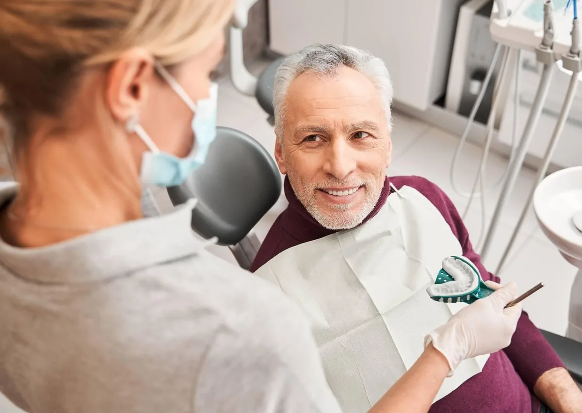 Dentist discussing denture options with an older patient while reviewing types and cost of dentures.