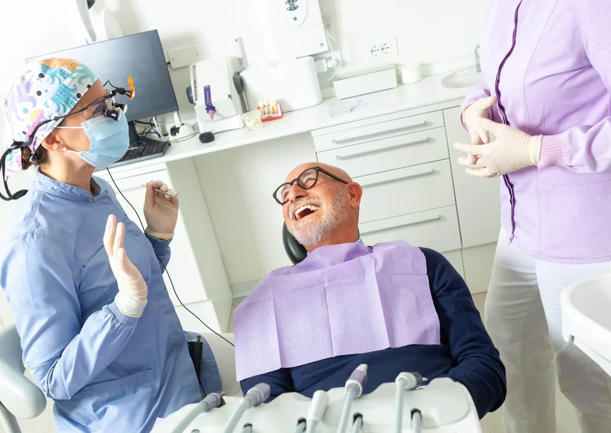 Patient discussing dentures vs. implants with a dental team to determine the right tooth replacement option.