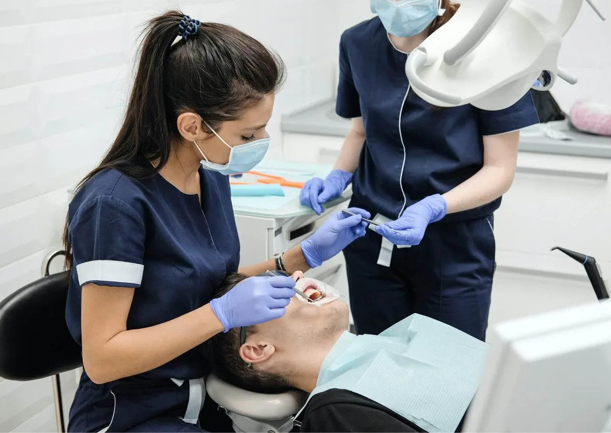 Dental team treating a patient during a stage of the tooth implant procedure and treatment timeline.