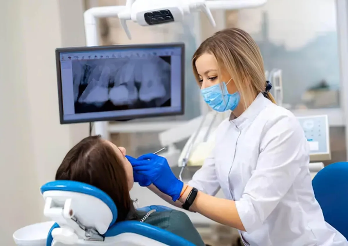 Dentist examining a patient and reviewing dental X-rays to discuss missing teeth replacement options.