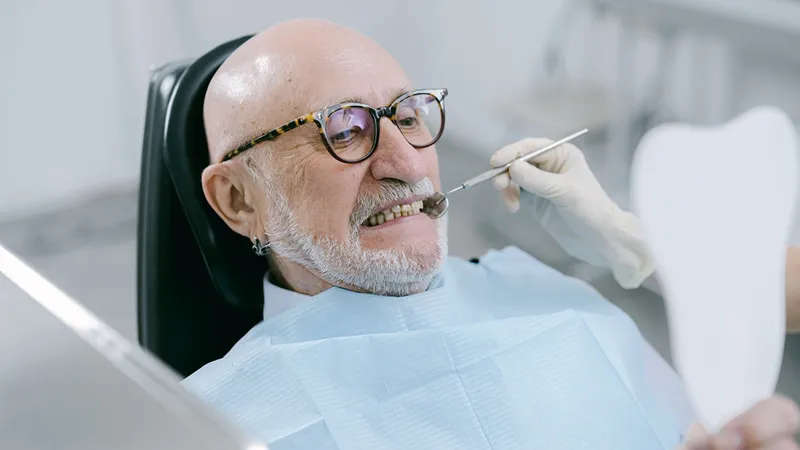 an old man at the dentist checking out his new smile