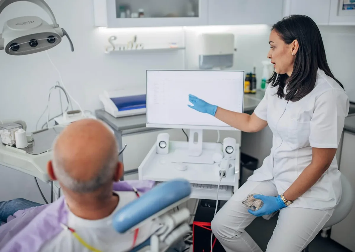 Dentist discussing full mouth dental implant treatment options and estimated costs with a patient during a consultation.