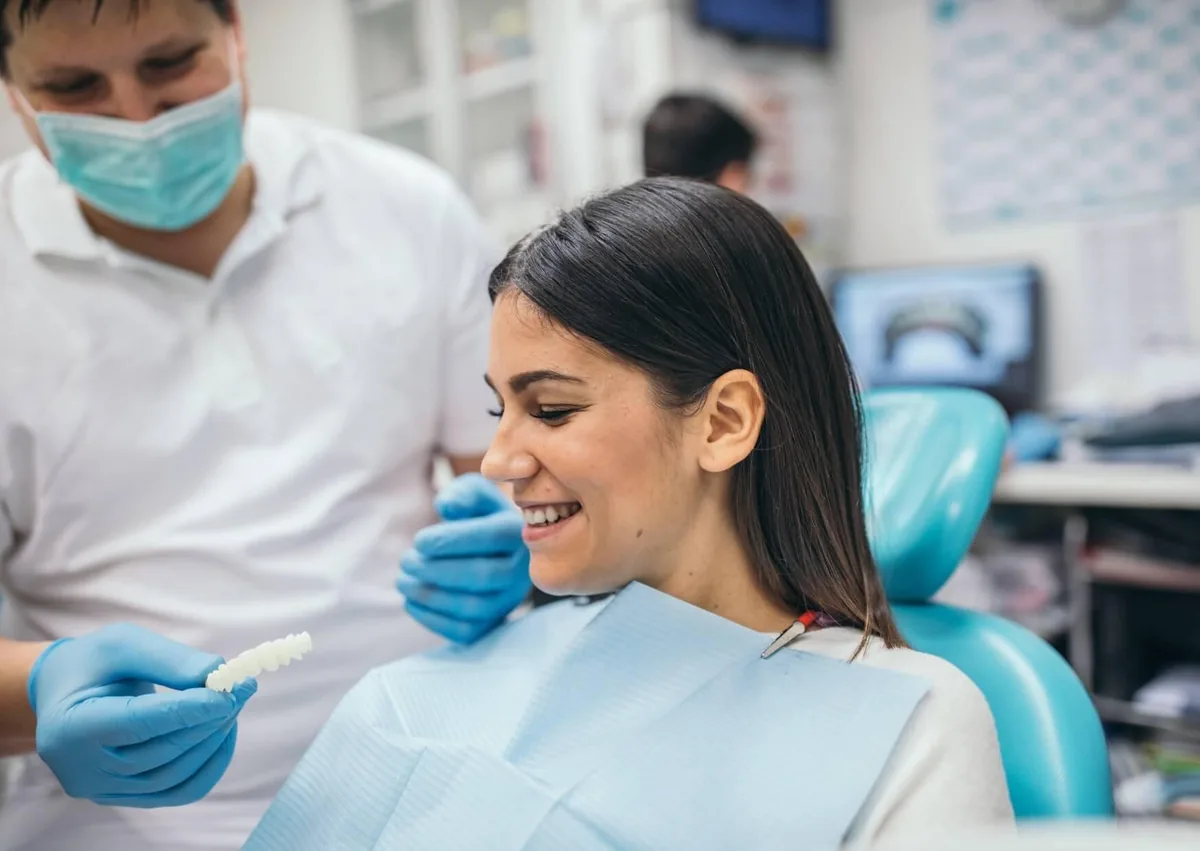 Dentist showing a patient a dental shade guide during a smile makeover consultation to plan her desired results.