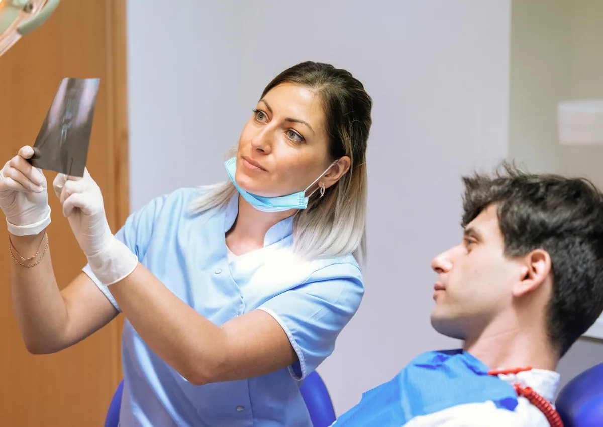 Dental professional reviewing an X-ray with a patient to assess jawbone structure and suitability for zygomatic dental implants.